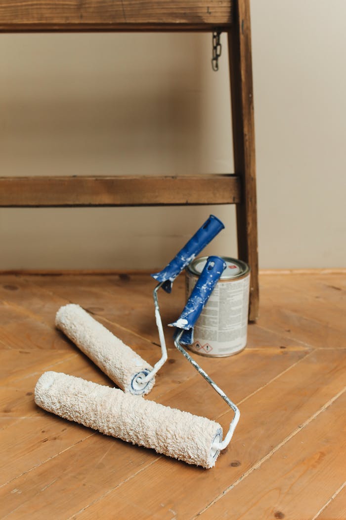 our-mission Paint rollers and can on a wooden floor, perfect for DIY home renovation projects.